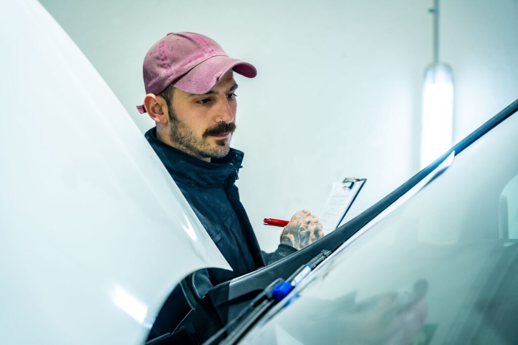 car mechanic inspecting vehicle damage and writing 2026 03 08 00 39 12 utc Car Window Replacement